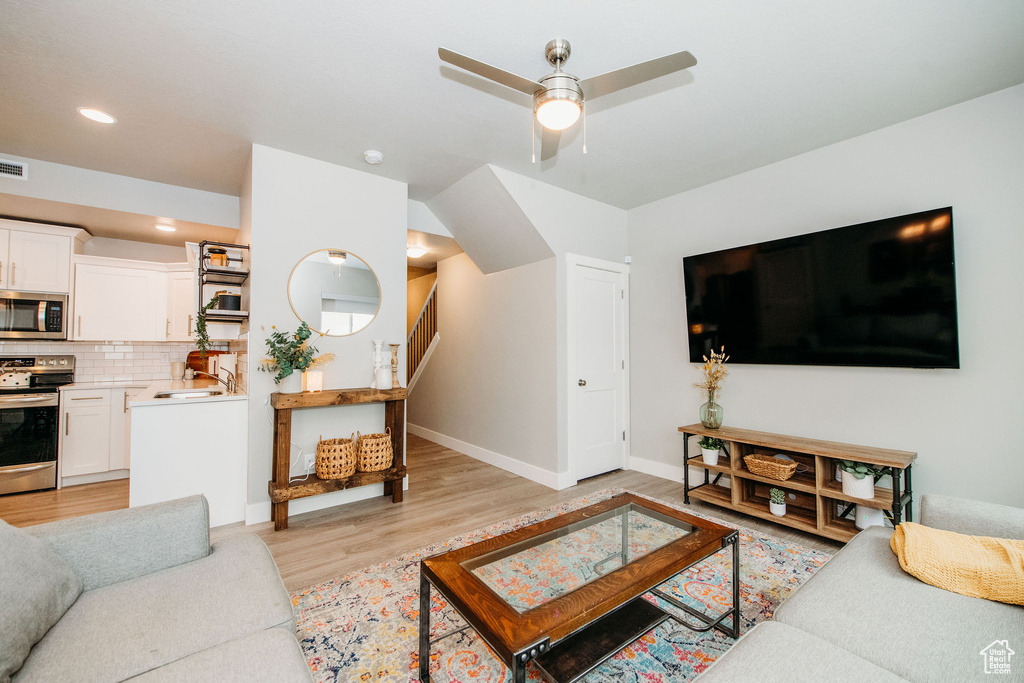 Living room with a ceiling fan, light wood-type flooring, and recessed lighting