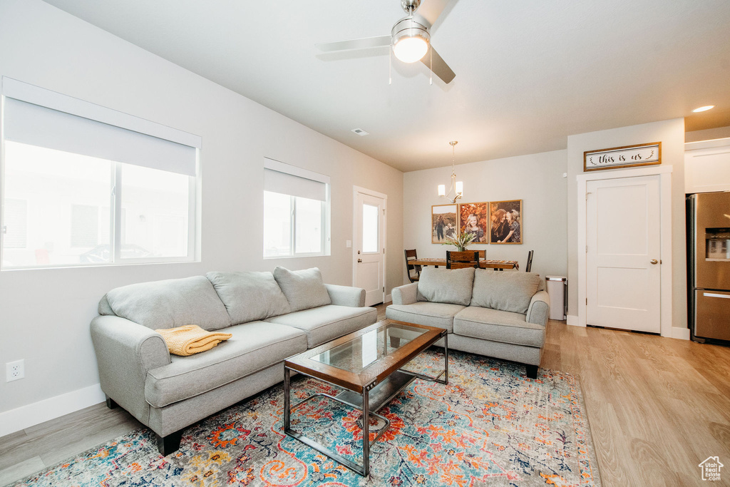 Living room with light wood-style flooring, a chandelier, and a ceiling fan