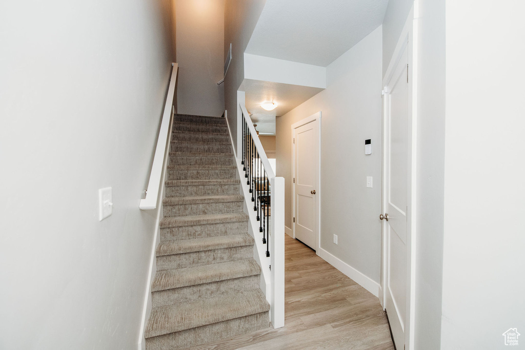 Staircase with wood finished floors and baseboards