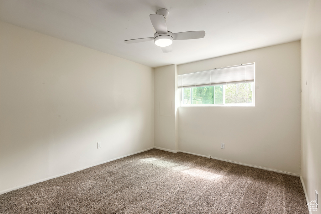 Carpeted spare room featuring ceiling fan and baseboards