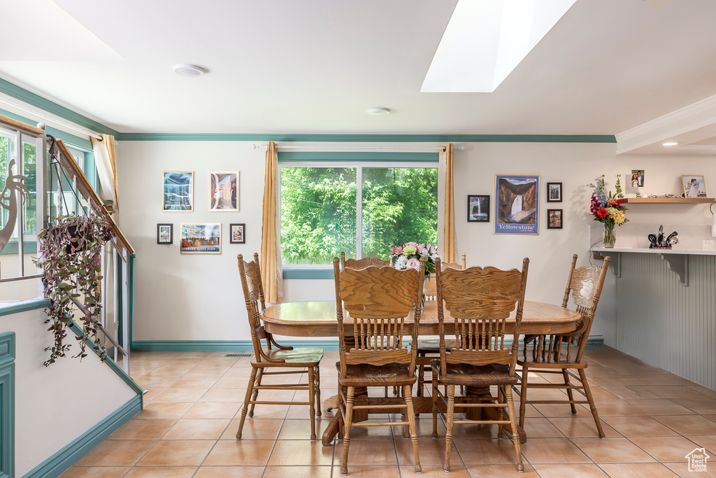 Dining room featuring light tile patterned floors, a skylight, and ornamental molding
