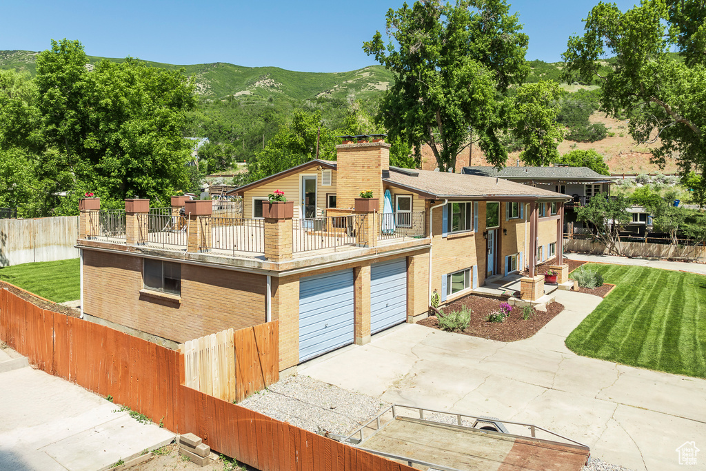 View of front of property featuring a balcony, a garage, a chimney, a mountain view, and concrete driveway