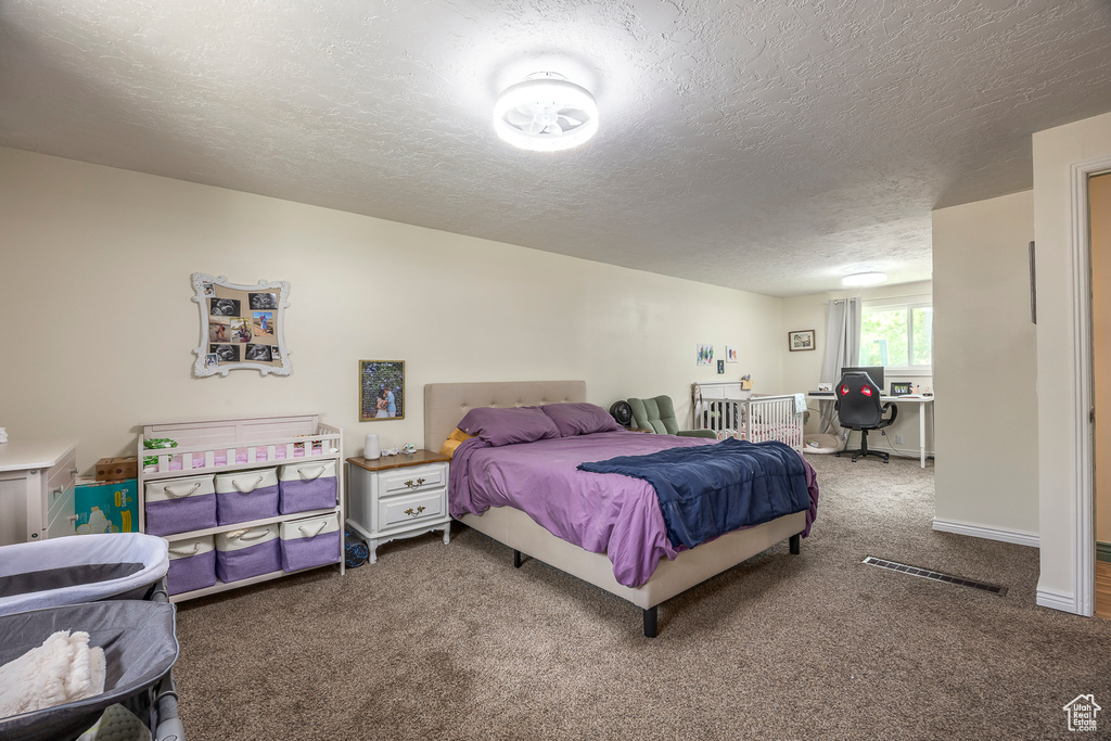 Carpeted bedroom with a textured ceiling and a desk