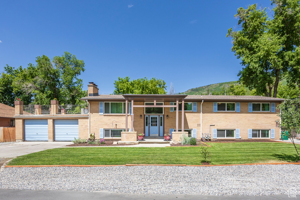 View of front of property with driveway, an attached garage, a chimney, and brick siding