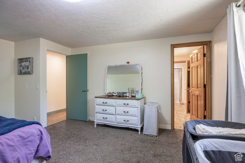 Bedroom with dark colored carpet and a textured ceiling