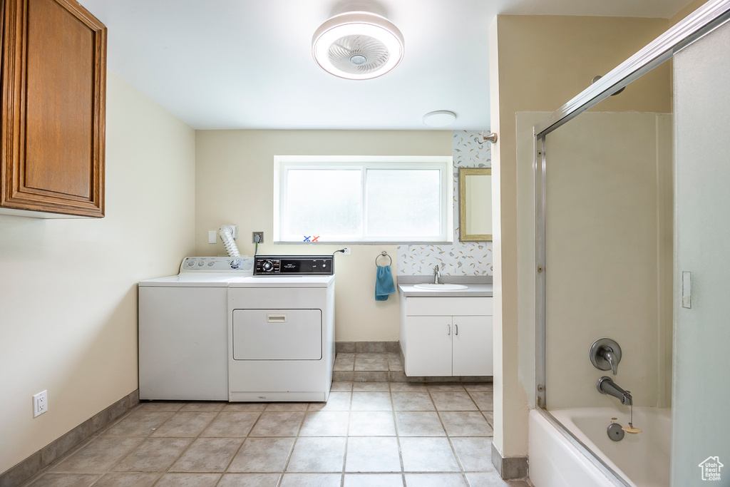 Laundry room with independent washer and dryer and light tile patterned floors