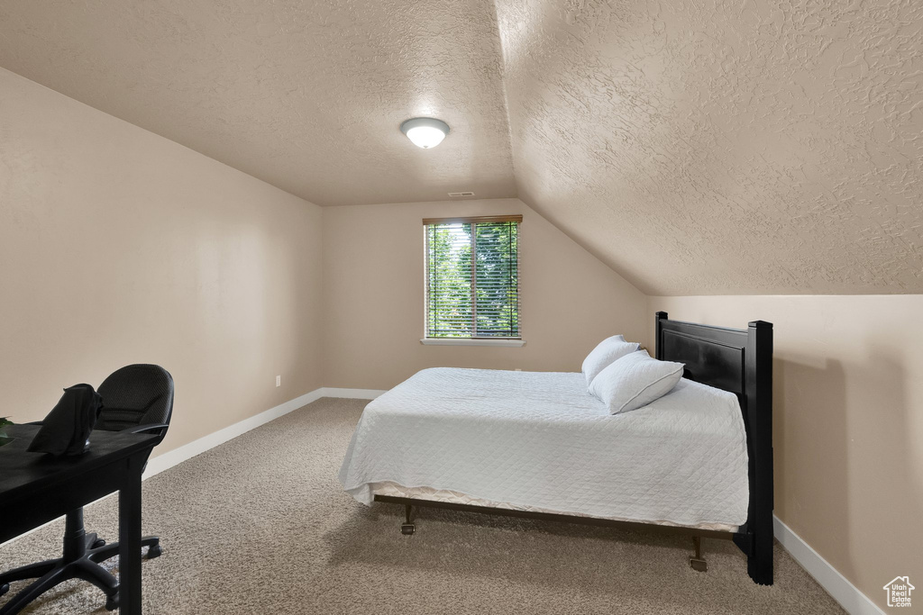 Bedroom featuring a textured ceiling, carpet flooring, and vaulted ceiling