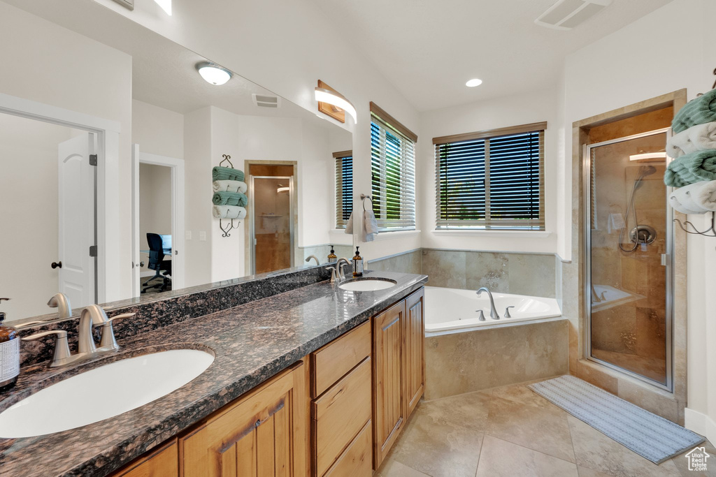 Full bathroom featuring a shower stall, a bath, double vanity, and tile patterned floors