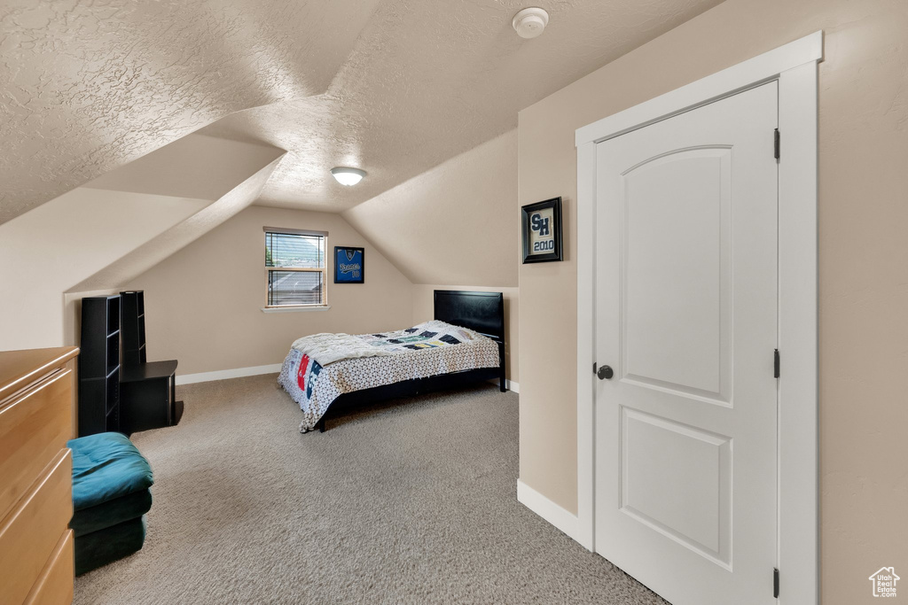 Bedroom featuring a textured ceiling, carpet, and lofted ceiling