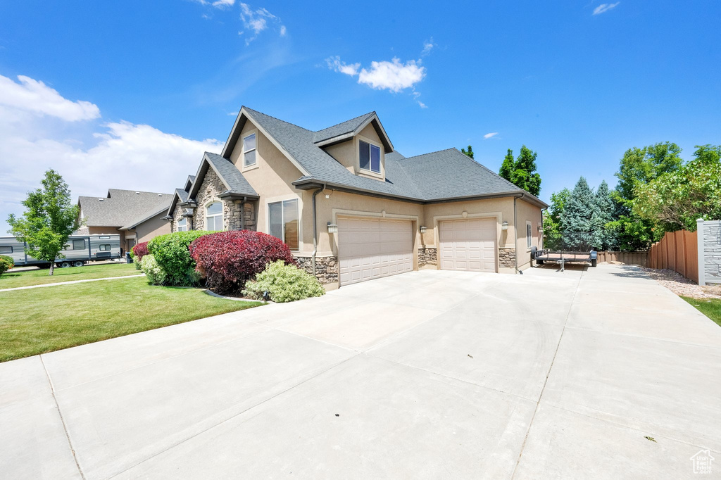 View of front of property featuring stone siding, stucco siding, concrete driveway, and an attached garage