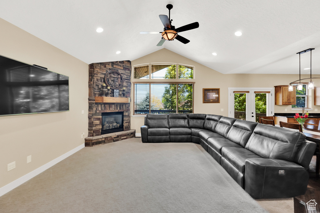 Living area with plenty of natural light, lofted ceiling, recessed lighting, a stone fireplace, and a ceiling fan