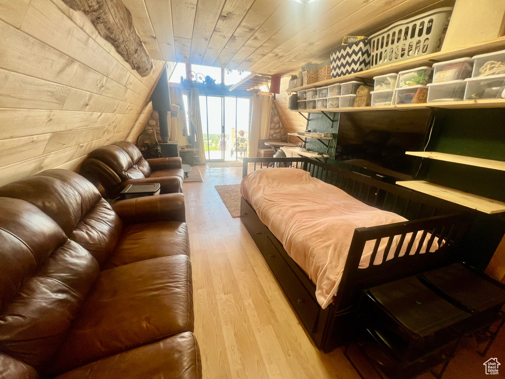 Bedroom with wood finished floors, wooden ceiling, wooden walls, floor to ceiling windows, and access to exterior