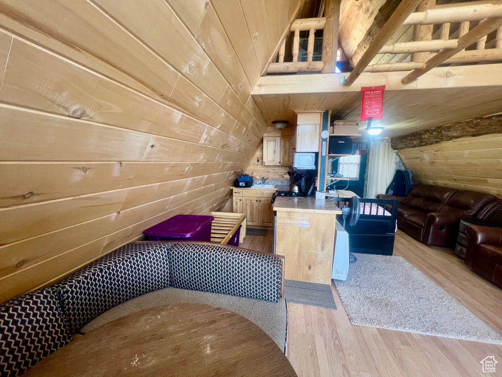 Bonus room featuring wooden walls, light wood-style flooring, and lofted ceiling