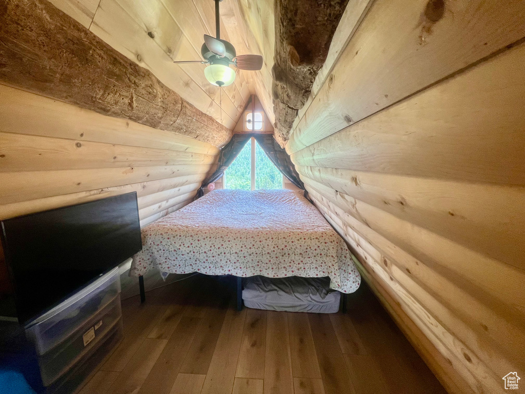 Bedroom with lofted ceiling, hardwood / wood-style flooring, and wooden walls