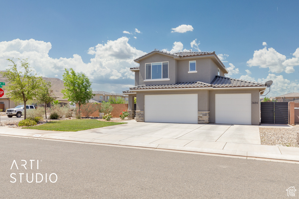 Mediterranean / spanish house with stucco siding, a tile roof, concrete driveway, stone siding, and an attached garage