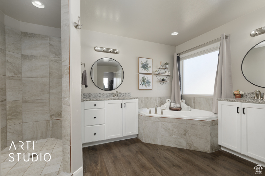 Full bath with a garden tub, wood finished floors, two vanities, a tile shower, and recessed lighting