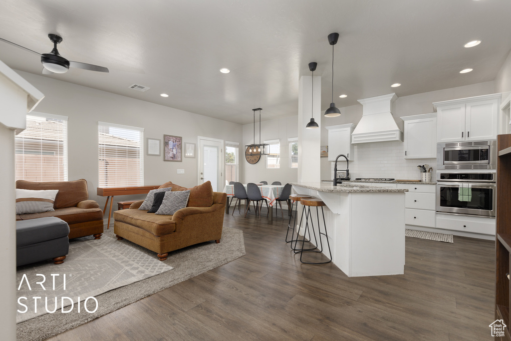 Living room featuring dark wood-type flooring, recessed lighting, ceiling fan, and a chandelier