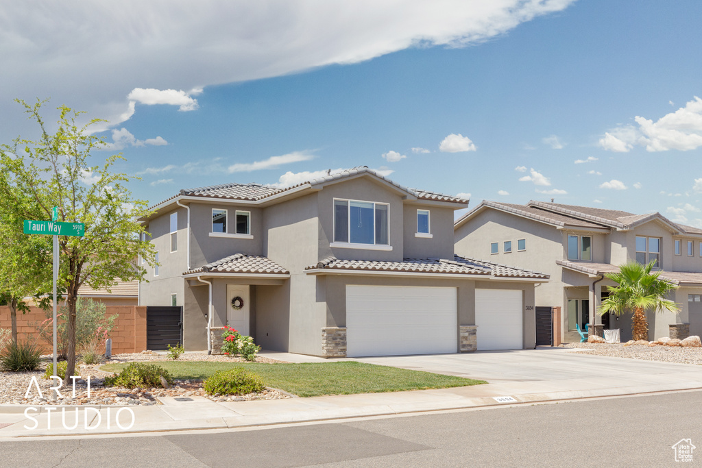 Mediterranean / spanish-style home featuring an attached garage, a tiled roof, concrete driveway, stucco siding, and stone siding