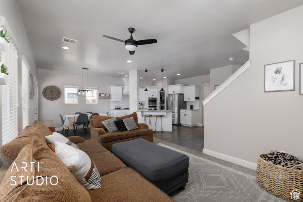 Living area with a ceiling fan, recessed lighting, and dark colored carpet