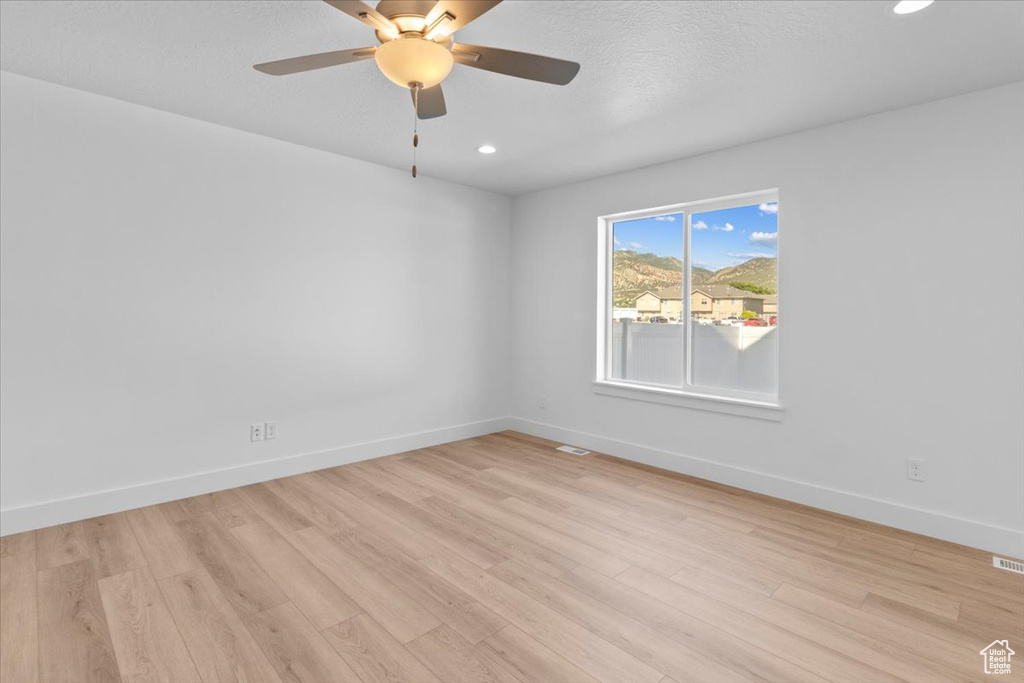 Empty room with light wood-style flooring, ceiling fan, and recessed lighting