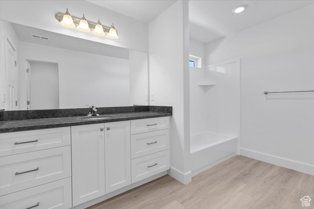 Bathroom with wood finished floors, vanity, shower / tub combination, and recessed lighting