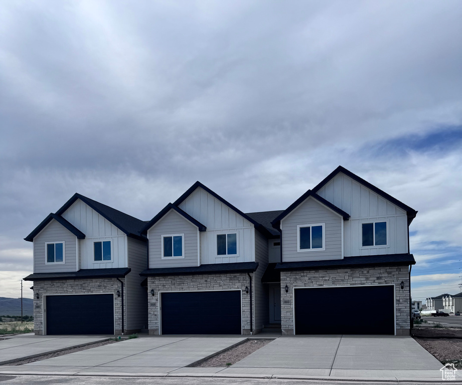 View of front of house with an attached garage, stone siding, and board and batten siding