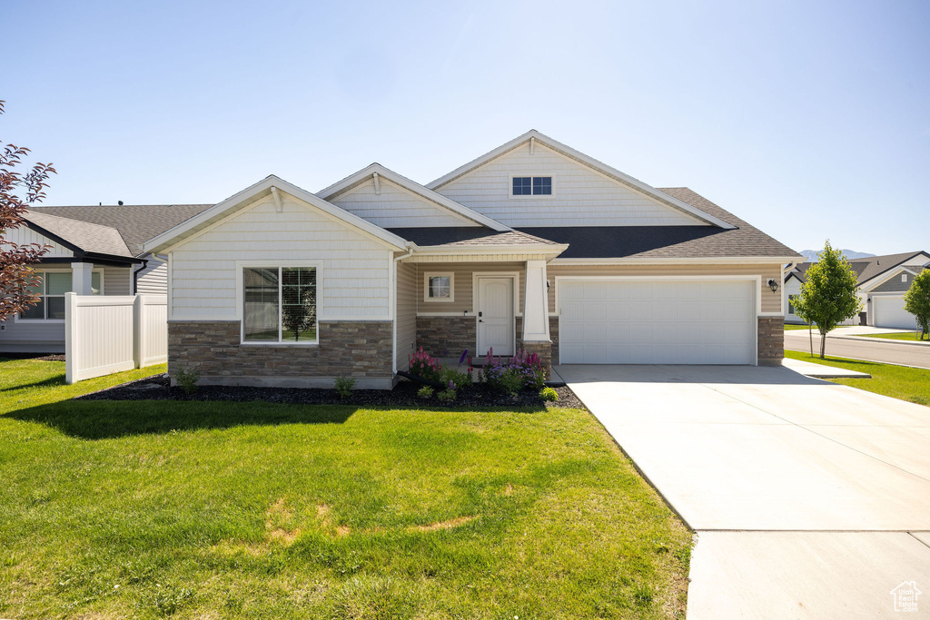 Craftsman inspired home with stone siding, an attached garage, concrete driveway, a front yard, and roof with shingles