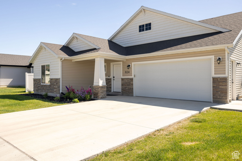 View of front of house with stone siding, roof with shingles, concrete driveway, an attached garage, and a porch