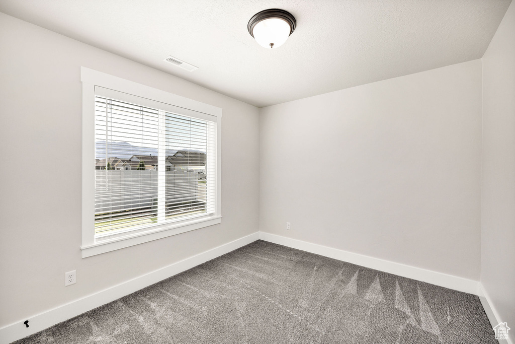 Empty room featuring dark colored carpet