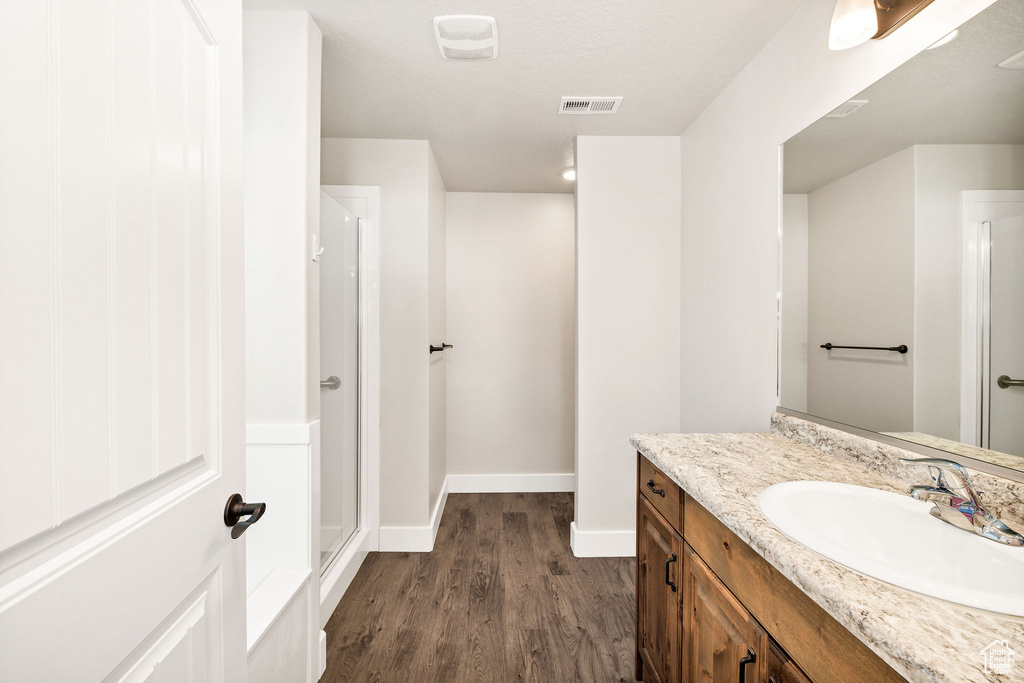 Full bathroom featuring wood finished floors, vanity, and a shower stall