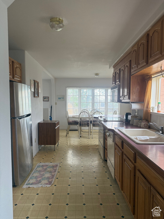 Kitchen featuring freestanding refrigerator, dishwashing machine, healthy amount of natural light, and dark countertops
