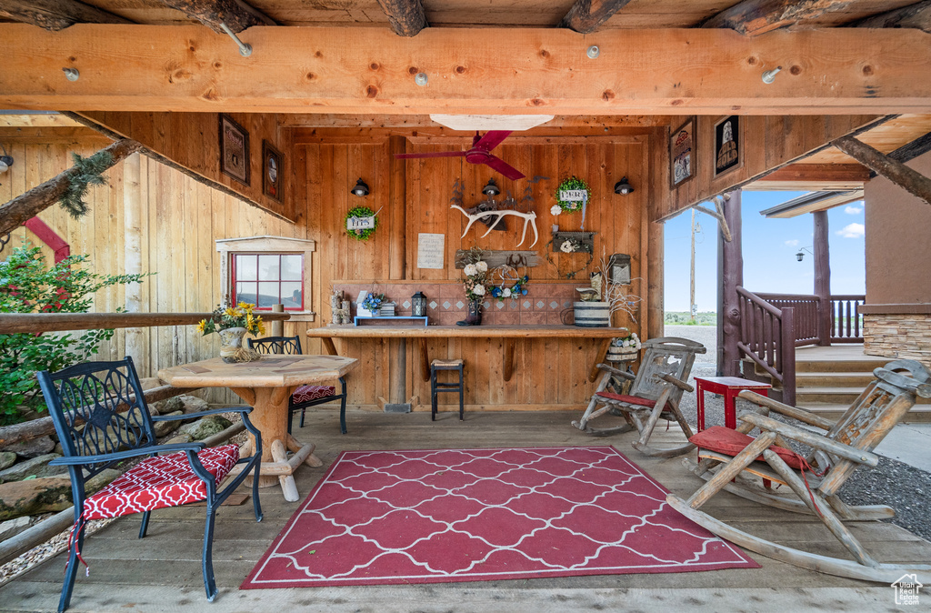 Dining area with beamed ceiling, wooden walls, and wood finished floors