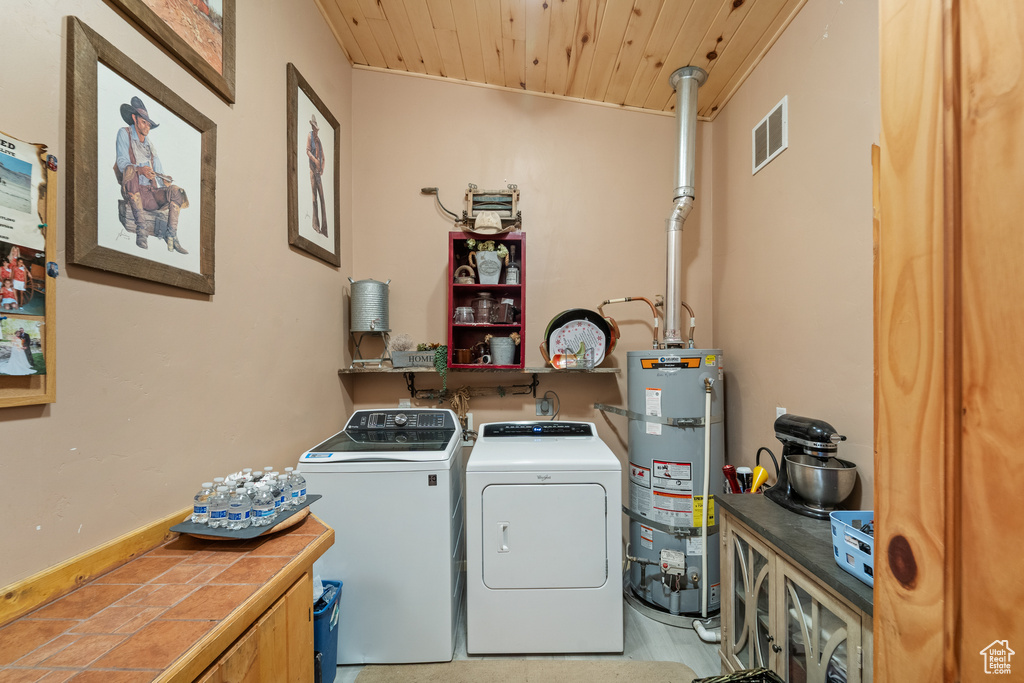 Washroom featuring secured water heater, wooden ceiling, and washer and clothes dryer
