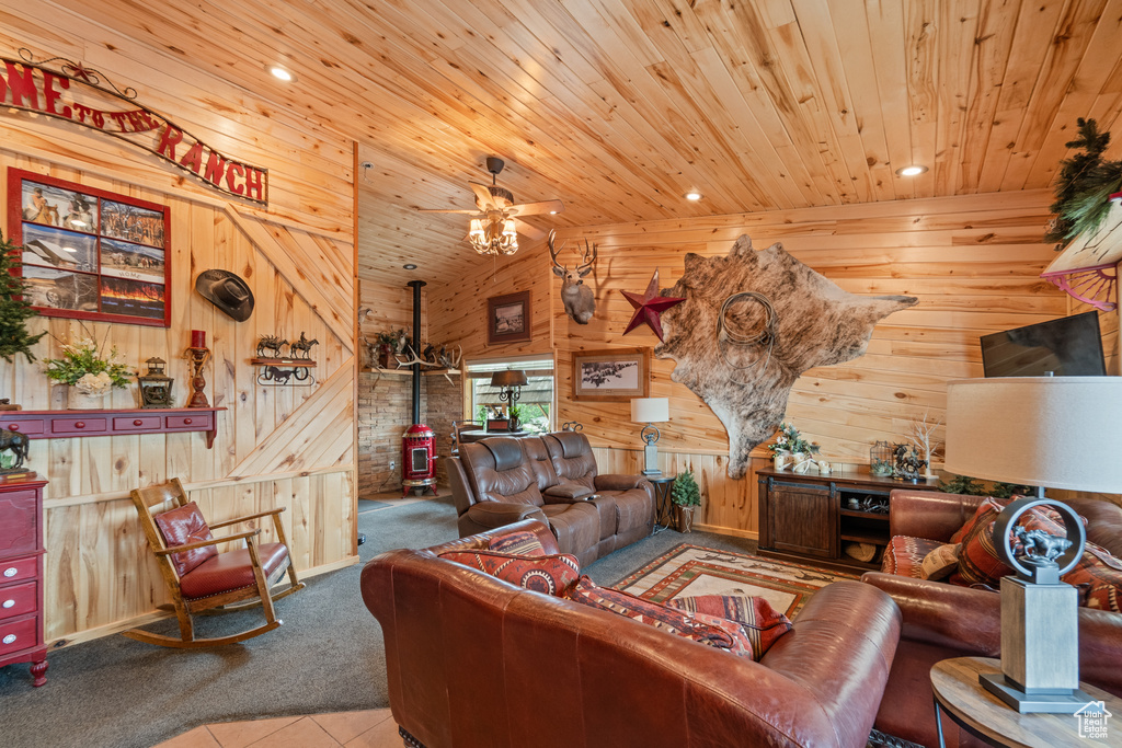 Carpeted living area with wood ceiling, wooden walls, a wood stove, vaulted ceiling, and a ceiling fan