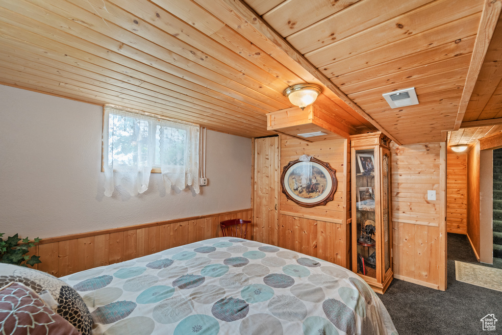 Bedroom with wood ceiling, wood walls, and carpet floors