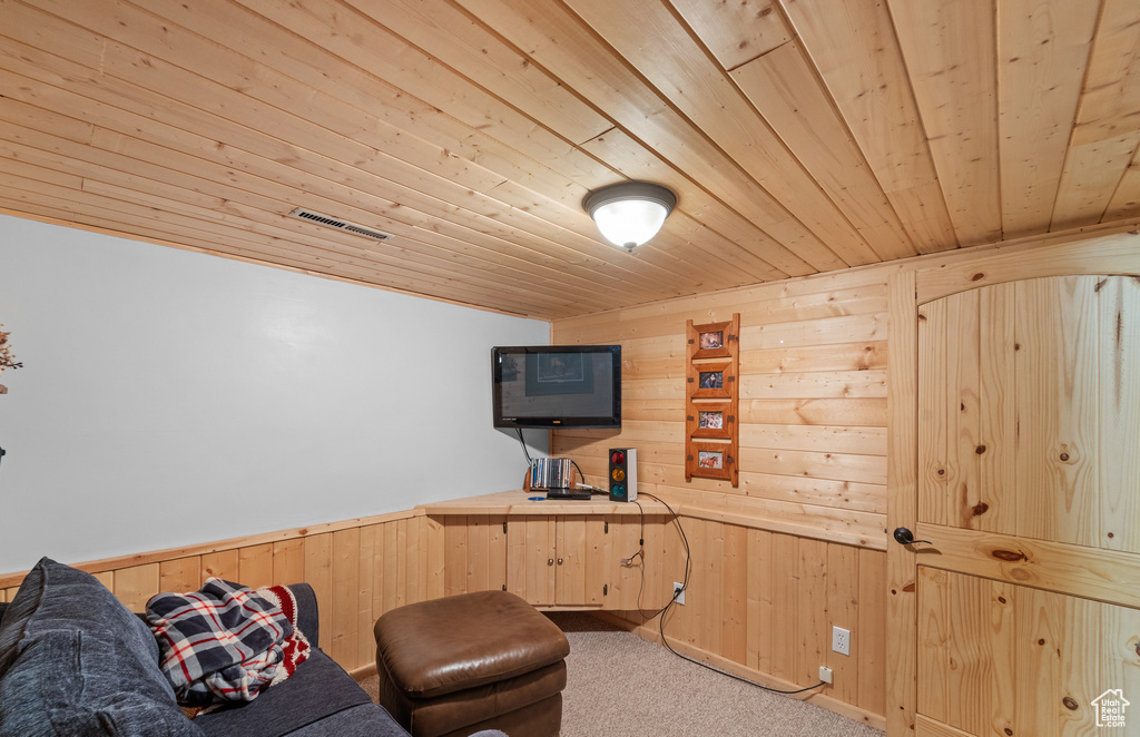 Living area featuring wooden ceiling, wooden walls, and carpet flooring