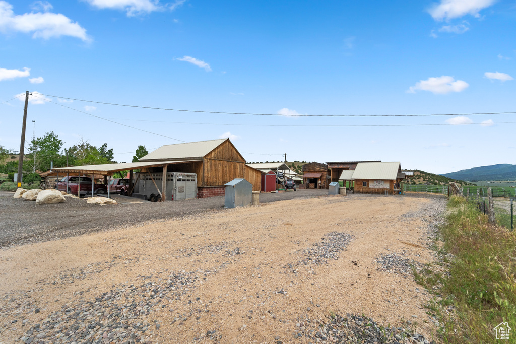 View of outbuilding with a carport, dirt driveway, and a mountain view