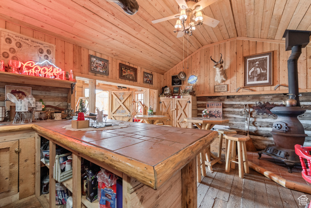 Dining room with vaulted ceiling, wood ceiling, wooden walls, hardwood / wood-style floors, and a ceiling fan