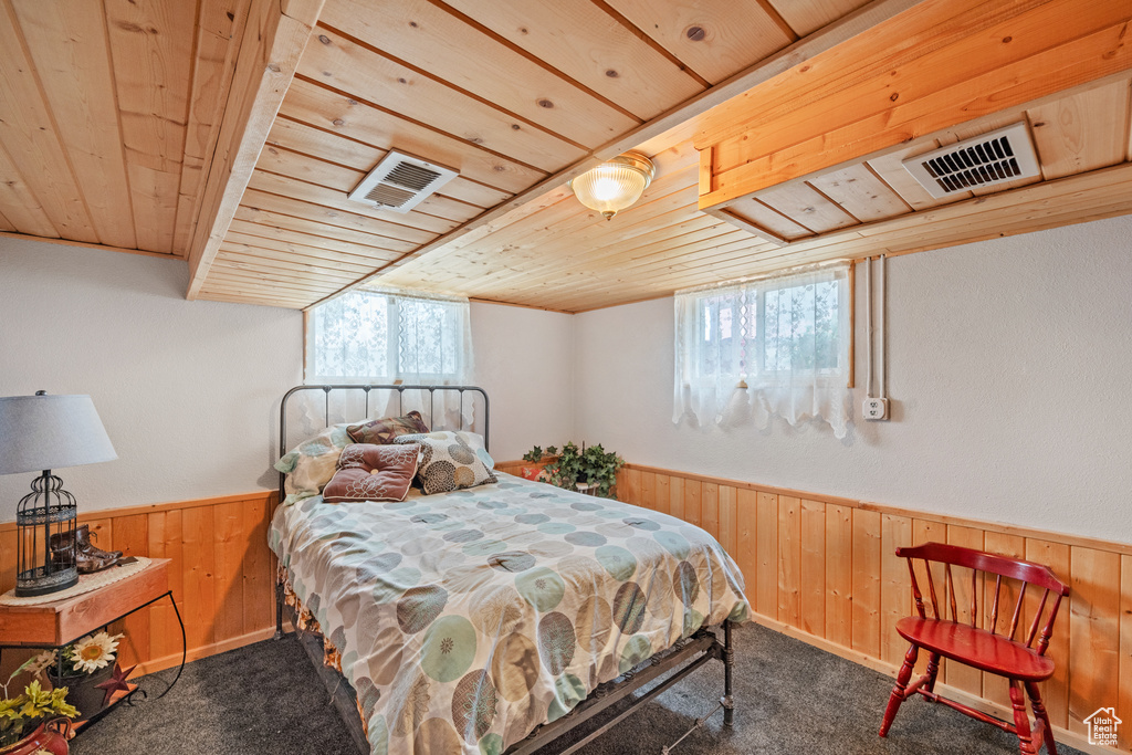 Bedroom featuring wooden ceiling, wooden walls, carpet flooring, and a wainscoted wall