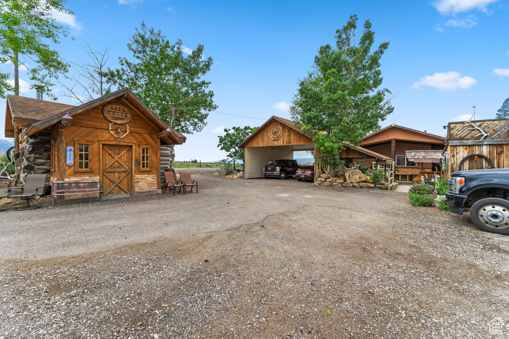 View of front of house featuring a carport, driveway, and log siding