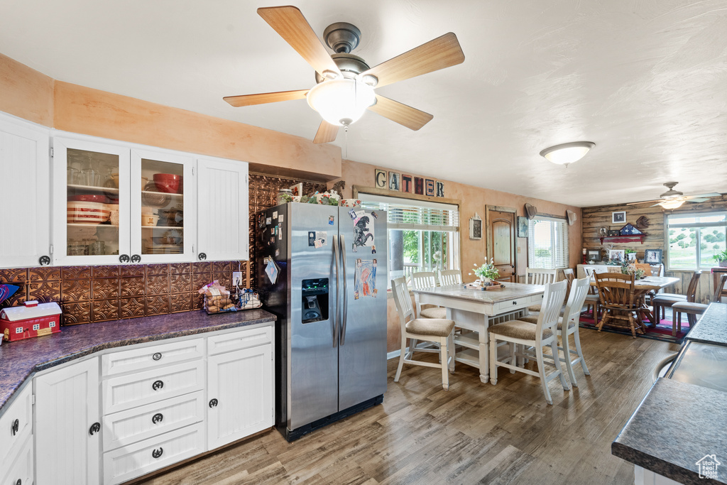 Kitchen featuring stainless steel refrigerator with ice dispenser, a ceiling fan, white cabinets, and wood finished floors