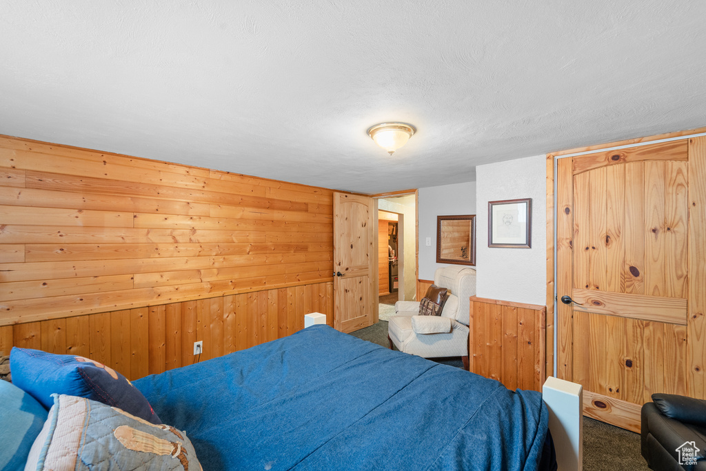 Carpeted bedroom with wooden walls and a textured ceiling