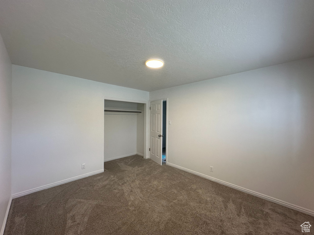 Unfurnished bedroom with carpet floors, a closet, and a textured ceiling