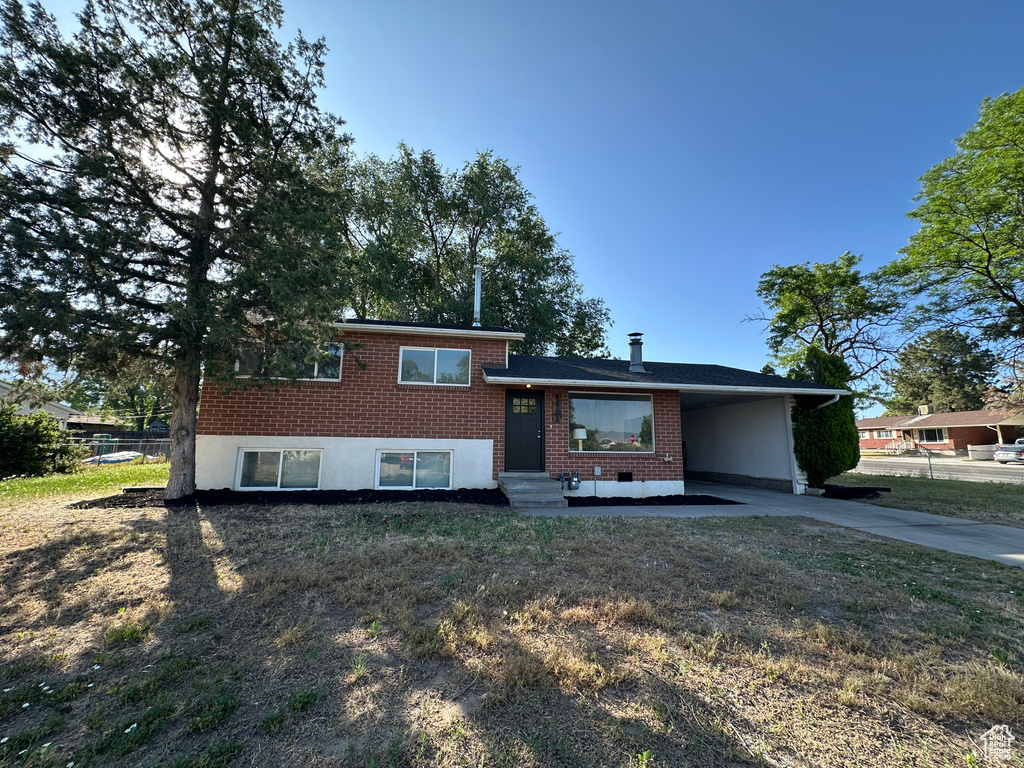 Split level home with brick siding, concrete driveway, an attached carport, and entry steps