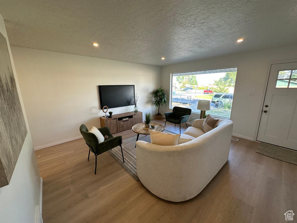 Living area featuring a textured ceiling, light wood-type flooring, and recessed lighting