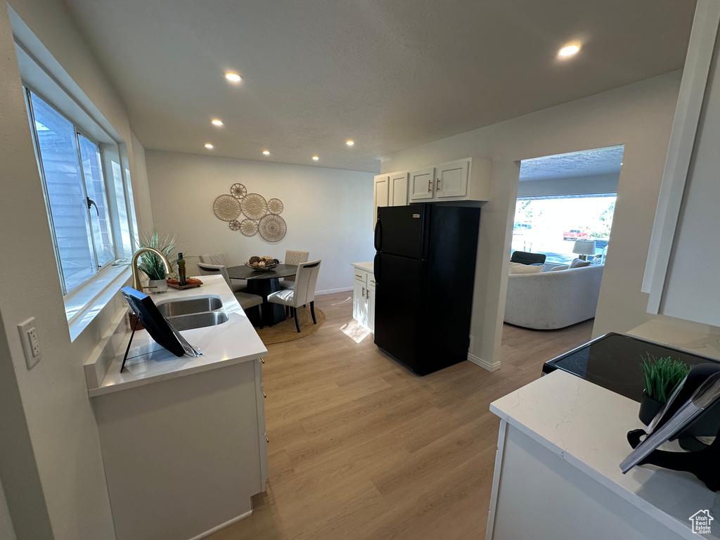Kitchen featuring freestanding refrigerator, recessed lighting, white cabinets, light wood-style flooring, and stove