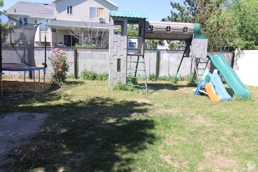 View of yard with a trampoline and a playground