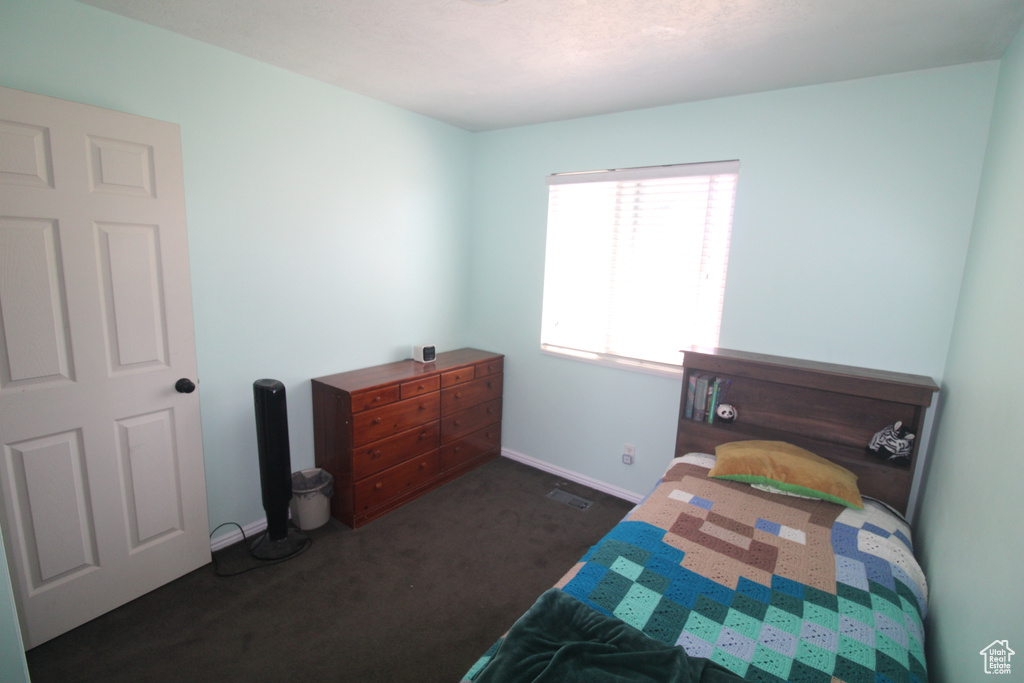 Bedroom with dark colored carpet and baseboards