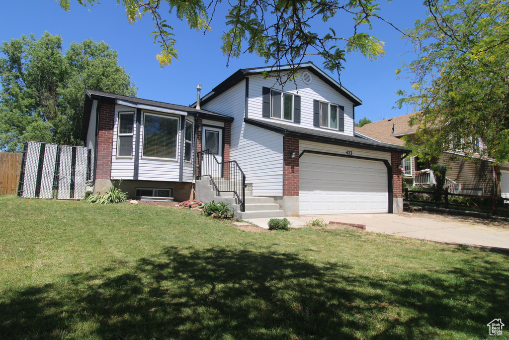 Split level home featuring a garage, driveway, and brick siding
