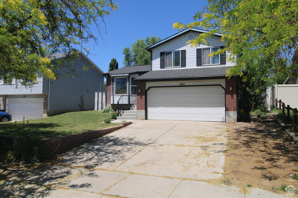 Tri-level home with an attached garage, concrete driveway, and brick siding